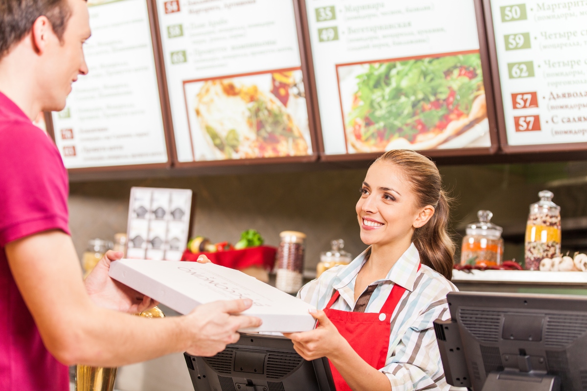 franchise pizza company employee handing a pizza to a customer